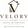 A centered brand logo for VELORY HOME on a plain white background, featuring a stylized brown house outline with a large V, a muted green geometric accent, and the text 'VELORY HOME' and 'Bedding and Home Goods' beneath.
